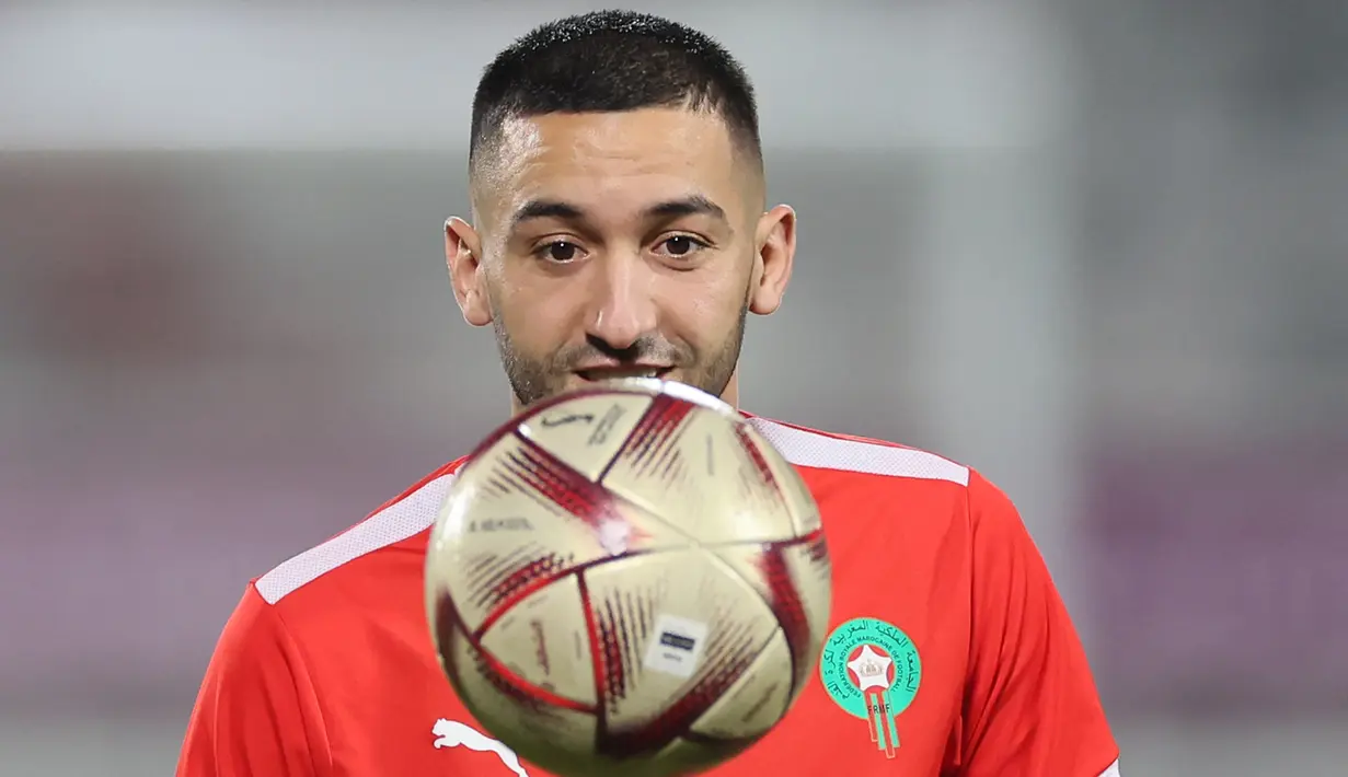 Gelandang Maroko, Hakim Ziyech menatap bola saat ia mengambil bagian dalam sesi latihan di Stadion Al Duhail SC di Doha pada 13 Desember 2022. Maroko akan bertanding melawan Prancis dalam pertandingan semifinal Piala Dunia 2022 di Stadion Al Bayt, Al Khor, Kamis (15/12/2022) pukul 02.00 WIB. (AFP/Karim Jaafar)