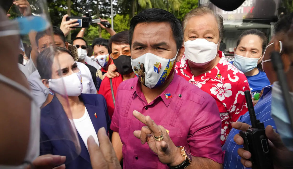 Pensiunan bintang tinju dan senator Filipina Manny Pacquiao (tengah) berbicara dengan polisi di samping istrinya Jinkee (kiri) sebelum mengajukan sertifikat pencalonannya untuk pemilihan presiden tahun depan di Komisi Pemilihan Umum, Manila, Filipina, Jumat (1/10/2021). (AP Photo/Aaron Favila)