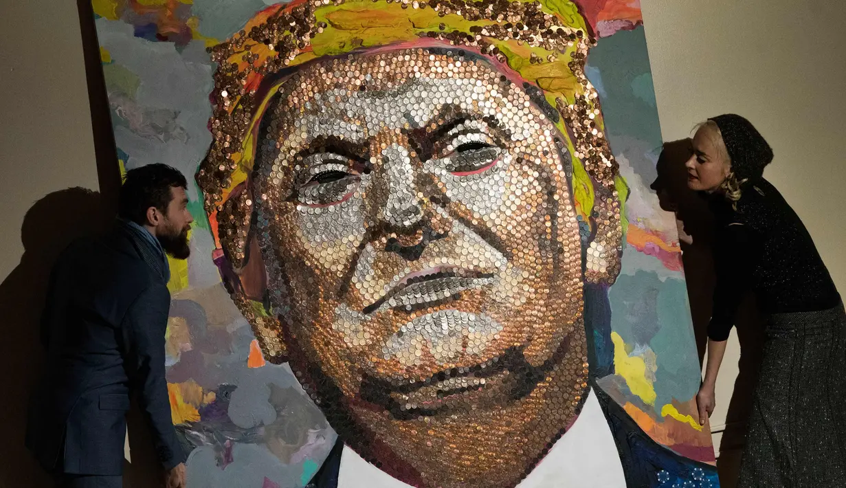 Seniman Ukraina Daria Marchenko dan Seniman Inggris Daniel Green menunjukkan lukisan Presiden AS Donald Trump yang terbuat dari rangkaian koin di Akademi St George di New York (30/1). (AFP Photo/Don Emmert)