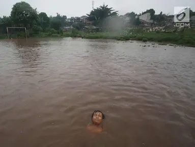Seorang anak bermain di lapangan yang terendam banjir di kawasan Kemang, Jakarta, Kamis (16/11). Tingginya intensitas hujan dan pesatnya pembangunan menyebabkan kawasan tersebut langganan banjir karena luapan Kali Krukut. (Liputan6.com/Immanuel Antonius)