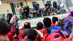 Peserta dari atas kereta kuda melempari jeruk kepada warga pada festival "Battaglia delle Arance" (Perang Jeruk) di kota kecil dekat Turin, Minggu (11/2). Acara tahunan ini tercatat sebagai festival tertua di Italia sejak tahun 1808. (MIGUEL MEDINA/AFP)