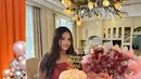 Saat mendapatkan kejutan buket bunga dan kue ulang tahun, Arlova mengenakan atasan merah bertekstur strapless dipadukan celana hitam pleated. [@erintaulany]
