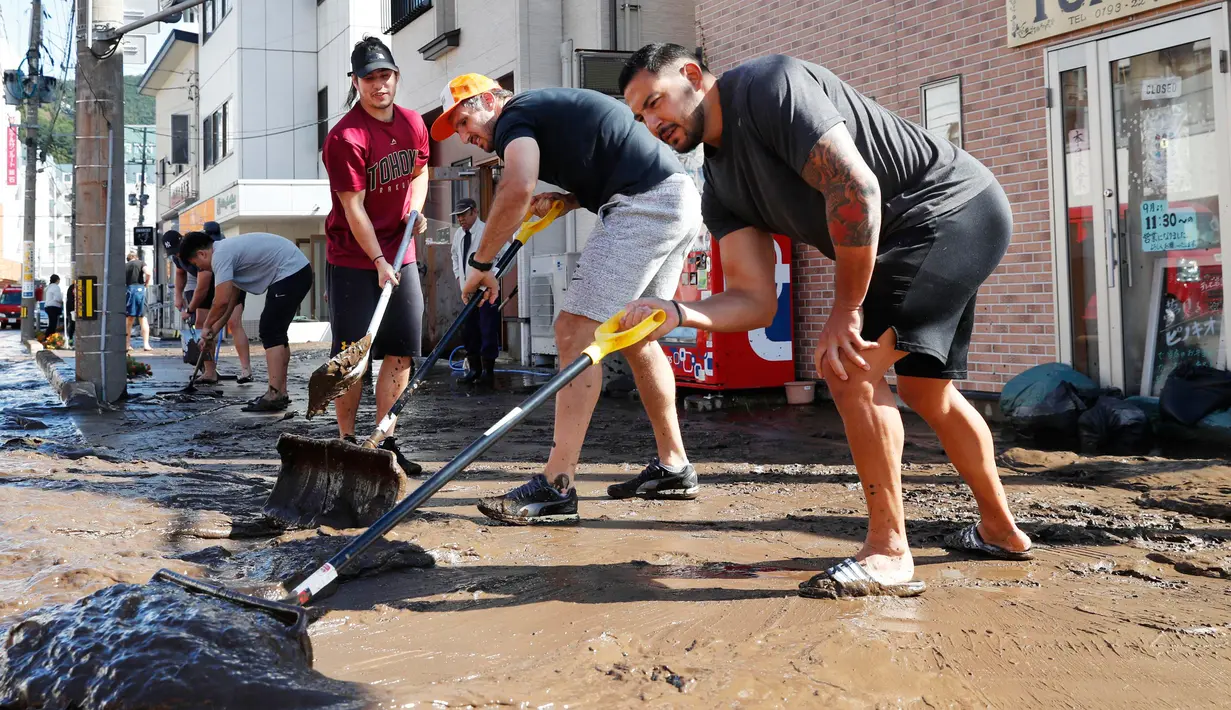 Para pemain rugby Kanada secara sukarela membersihkan jalan usai terjadi Topan Hagibis di Kamaishi, Prefektur Iwate, Jepang, Minggu (13/10/2019). Topan Hagibis membuat pertandingan Rugby World Cup Pool B antara Kanada dengan Namibia dibatalkan. (Kyodo News via AP)