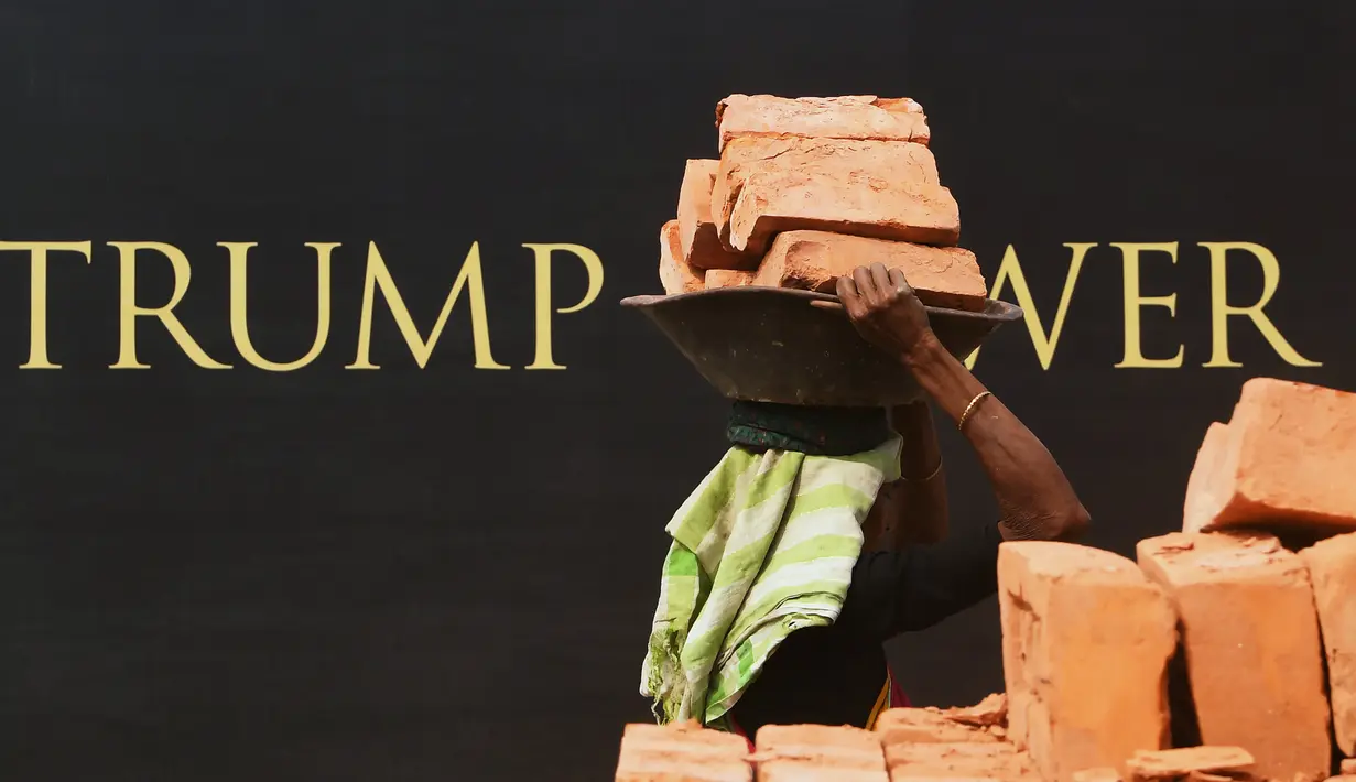 Seorang buruh wanita India mengangkat batu bata untuk pembangunan konstruksi Trump Tower atau Menara Trump di Kolkata, India (20/2). Trump Jr juga menjadi tuan rumah makan malam di Kolkata untuk menjamu para investor properti. (AFP/ Dibyangshu Sarkar)