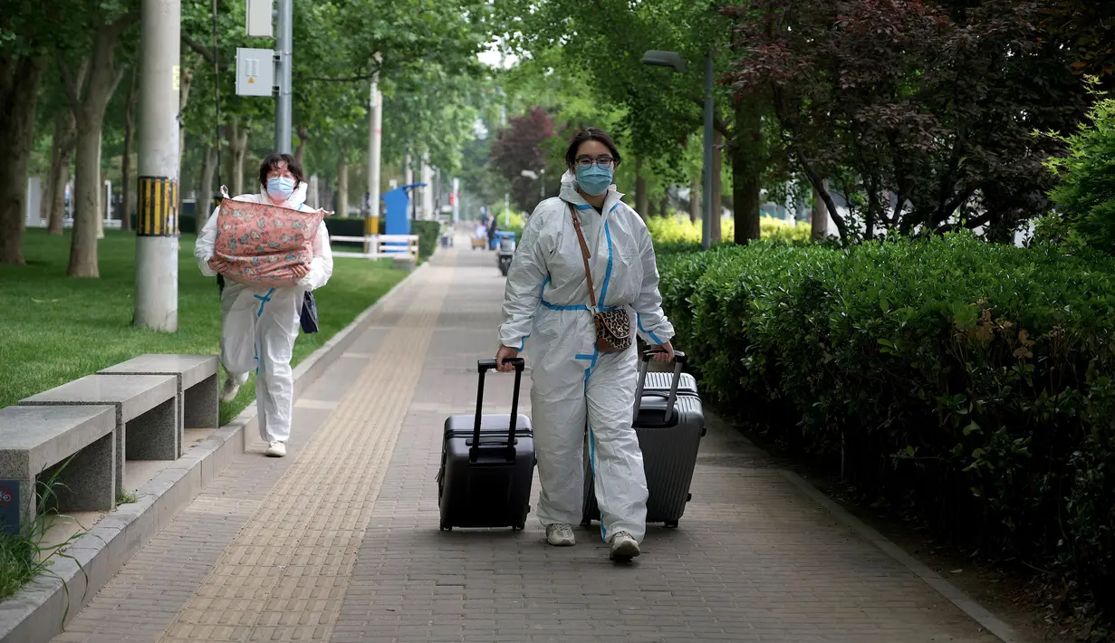 <p>Orang-orang yang memakai alat pelindung diri (APD) berjalan dengan barang bawaan mereka dekat area yang dikunci karena wabah virus corona COVID-19 baru-baru ini di Beijing, China, Selasa (10/5/2022). Jutaan orang di Beijing tinggal di rumah pada 9 Mei ketika Ibu Kota China tersebut mencoba untuk menangkis wabah COVID-19 dengan pembatasan pergerakan. (Noel Celis/AFP)</p>