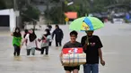Warga berjalan melewati banjir menyusul hujan lebat di distrik Ran-ngea di provinsi Narathiwat, Thailand selatan (26/2/2022).  Hujan yang disebabkan oleh angin timur laut di atas Teluk Thailand terus berlanjut selama tiga hari berturut-turut di provinsi perbatasan selatan ini. (AFP/Madaree Tohlala)