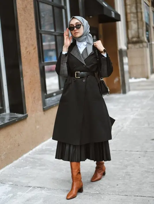 Untuk outfit semi formal, kamu bisa memadukan kemeja putih dan rok plisket hitam dengan outer berupa coat yang diberi ikat pinggang. Untuk sepatu, pilihlah knee length boots. Dijamin lookmu makin kece. (Instagram/elifd0gan).