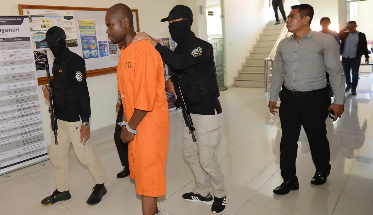 Abdul Rachman Azman asal Tanzania dikawal petugas sebelum konferensi pers di Kantor Pelayanan Bea Cukai Bandara Ngurah Rai, Bali, Selasa (12/2). Abdul menyelundupkan sabu dengan modus menelan 99 butir yang diperkirakan mencapai 1 kg. (Sonny TUMBELAKA/AFP)
