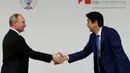 Presiden Rusia Vladimir Putin (Kiri) dan PM Jepang Shinzo Abe berjabat tangan saat preskon di Tokyo, Jepang, Jumat (16/12). Selain membahas soal wilayah sengketa, kedua belah pihak juga membahas situasi di semenanjung Korea. (REUTERS / Kim Kyung-Hoon)