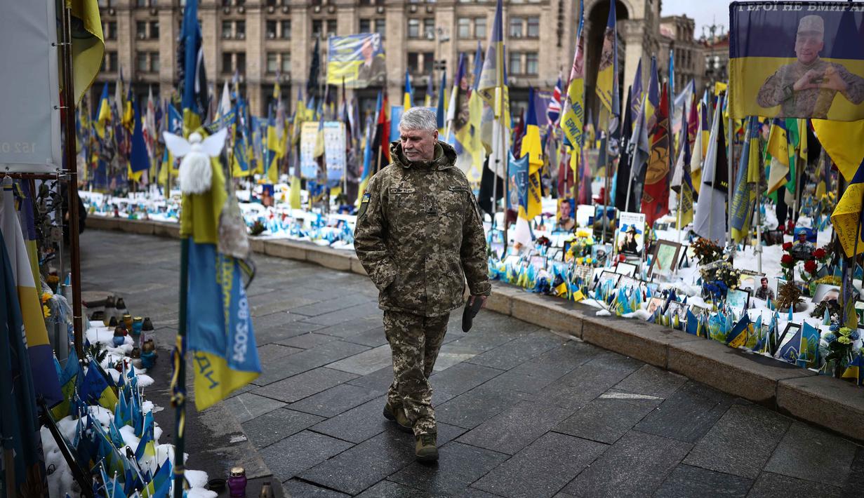 CSIS memperkirakan Rusia beban korban militer sebesar 1,2 juta orang, dengan 325.000 di antaranya tewas. Sementara, Ukraina mengalami kerugian personel hingga 600.000 orang, termasuk 140.000 prajurit yang gugur. Tampak dalam foto, seorang warga setempat mengunjungi tugu peringatan sementara untuk tentara Ukraina dan asing di Lapangan Kemerdekaan, Kyiv, saat peringatan keempat invasi Rusia ke Ukraina, Selasa 24 Februari 2026. (HENRY NICHOLLS/AFP)