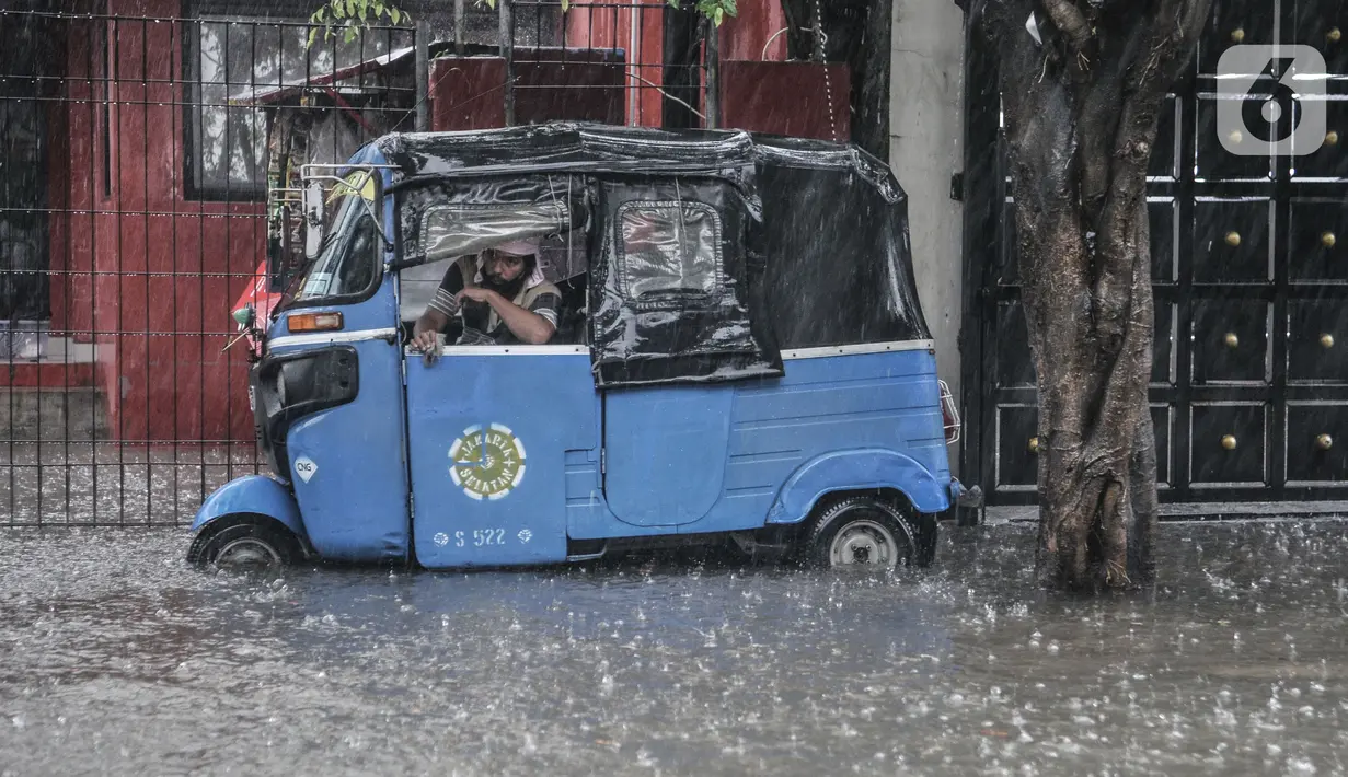 Sebuah bajaj saat terjebak banjir yang merendam Jalan Abdullah Syafei, Tebet, Jakarta, Kamis (18/2/2021). Banjir juga menyebabkan akses putar balik di kawasan dekat Stasiun Tebet itu terputus. (merdeka.com/Iqbal S Nugroho)