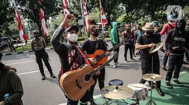 Sejumlah musisi kafe saat melaksanakan aksi di depan Balai Kota Jakarta, Rabu (8/7/2020). Aksi ngamen di depan Balai Kota Jakarta yang diikuti oleh musisi kafe itu untuk menyuarakan aspirasi pekerja seni harian yang terdampak mata pencahariannya selama masa PSBB. (Liputan6.com/Faizal Fanani)