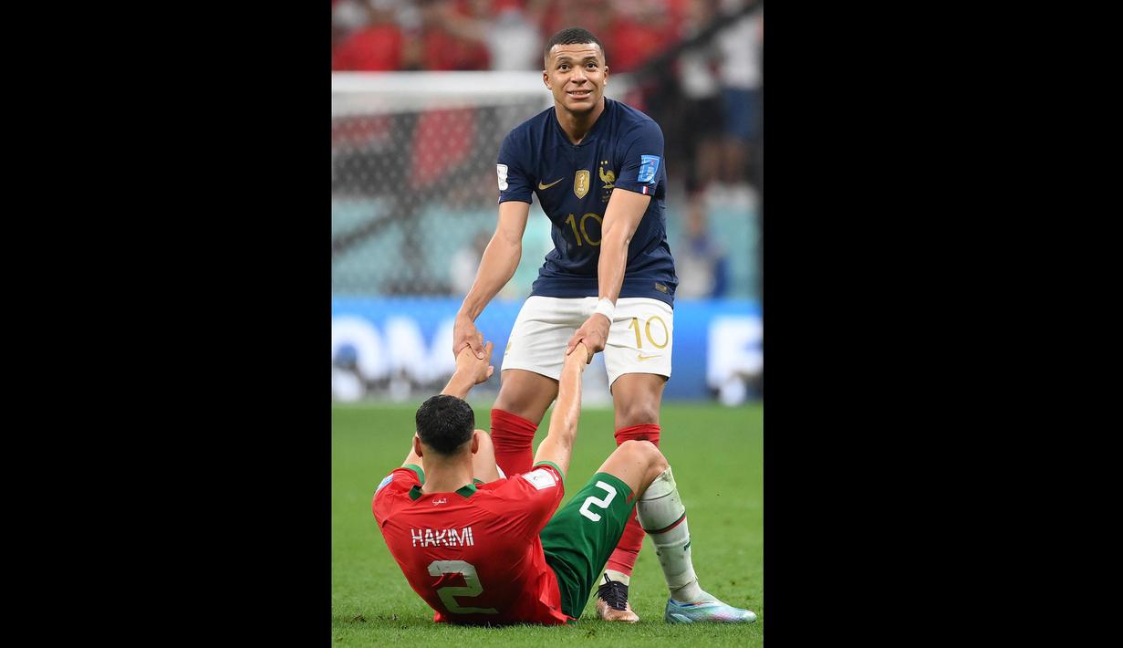 Pemain Prancis, Kylian Mbappe (kanan) berusaha membangunkan pemain Maroko, Achraf Hakimi setelah laga semifinal Piala Dunia 2022 yang berlangsung di Al Bayt Stadium, Qatar, Rabu (14/12/2022) waktu setempat. Prancis menang dengan skor 2-0 melalui gol Theo Hernandez dan Randal Kolo Muani. (AFP/Franck Fife)