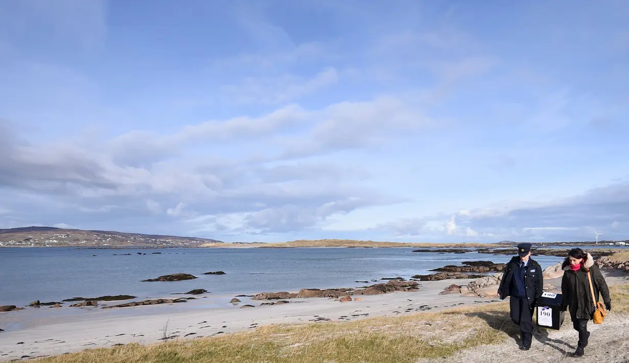 Polisi wanita Irlandia, Margaret Byrne dan pejabat ketua, Majella Harkin mengawal kotak suara ke pulau Innisfree, Irlandia, (25/2). Margaret seorang diri mengawal dan mengantarkan logistik pemilu ke pulau terpencil Irlandia. (REUTERS/Clodagh Kilcoyne)