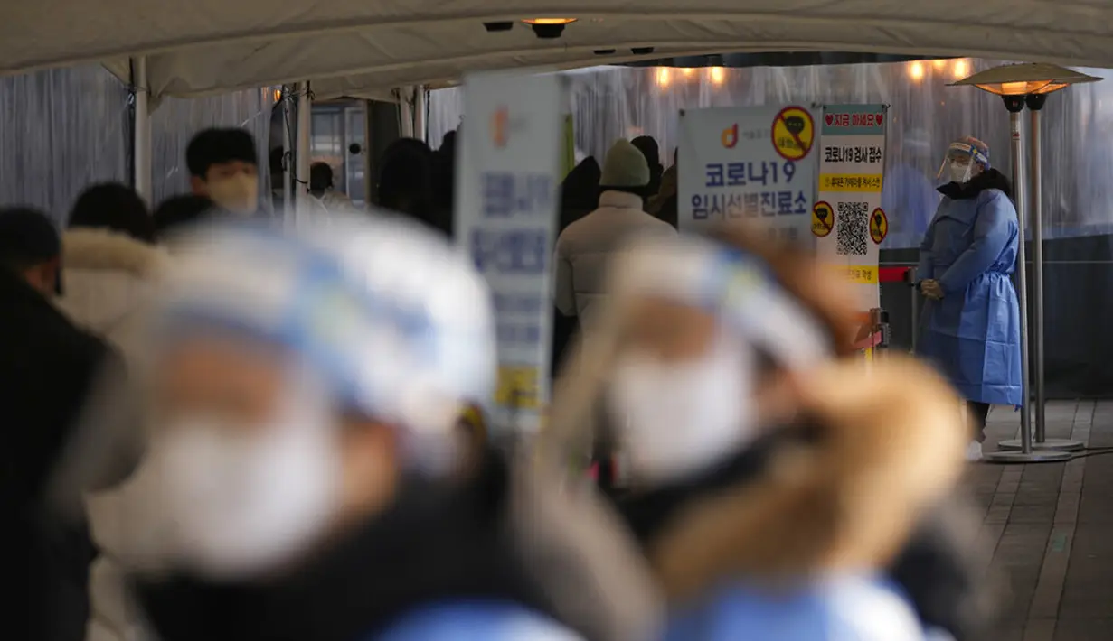 Petugas kesehatan yang mengenakan alat pelindung diri berdiri untuk membantu pengunjung di klinik skrining sementara untuk virus corona dekat Balai Kota Seoul, Seoul, Korea Selatan, Rabu (26/1/2022). (AP Photo/Lee Jin-man)