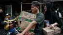 Airlangga mengungkap pemerintah juga telah menyalurkan bantuan sosial senilai hampir Rp 30 triliun sebagai salah satu upaya memperkuat daya beli masyarakat. Tampak dalam foto, seorang pria memegang kotak-kotak di antara lengannya sambil mengendarai motor setelah berbelanja di kios pinggir jalan di Jakarta pada Sabtu 8 November 2025. (YASUYOSHI CHIBA/AFP)