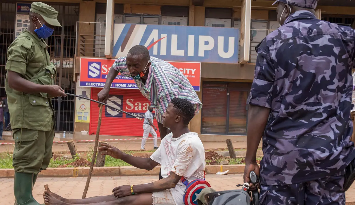 Aparat kepolisian menangkap pemuda yang masih berkeliaran di Kampala, Uganda (26/3/2020). Presiden Uganda Yoweri Museveni mengimbau masyarakatnya untuk tinggal di rumah selama 32 hari setelah 14 kasus positif Covid-19 teridentifikasi di negara tersebut. (AFP/Badru Katumba)