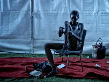 Model mengikatkan sandalnya di belakang panggung Dakar Fashion Week di ibukota Senegal, (1/7). Menurut data Euromonitor dunia fashion di Sub-Sahara Afrika telah berkembang pesat selama dua dekade terakhir. (AP Photo / Finbarr O'Reilly)