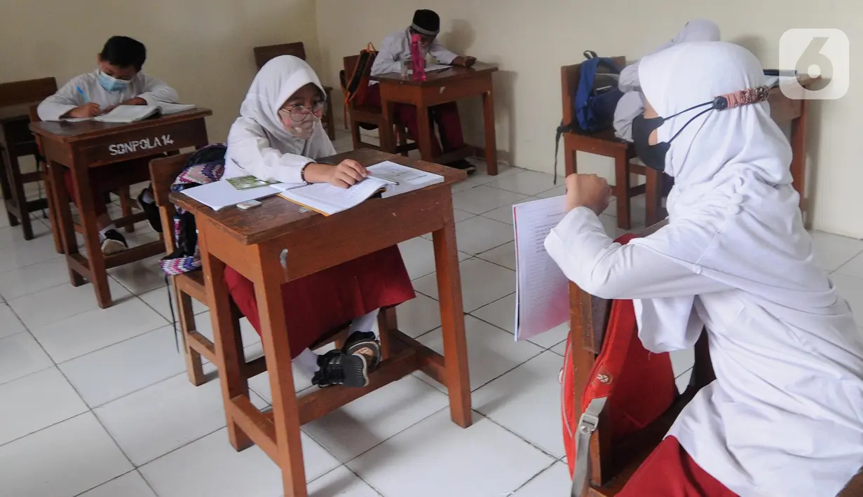 Murid kelas IV menunjukkan hasil tesnya kepada temannya yang belajar online di rumah saat kegiatan belajar tatap muka di SDN Pondok Labu 14 Pagi di Cilandak, Jakarta Selatan, Jumat (4/6/2021). (merdeka.com/Arie Basuki)