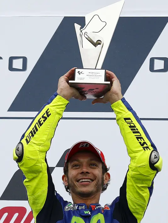 Pembalap Yamaha, Valentino Rossi saat mengangkat piala kemenangan setelah menjadi yang terdepan di Moto Gp seri ke-12 di sirkuit Silverstone (30/8/2015). Posisi kedua dan ketiga diduduki Danilo Petrucci dan  Andrea Dovizioso. (REUTERS/Darren Staples)
