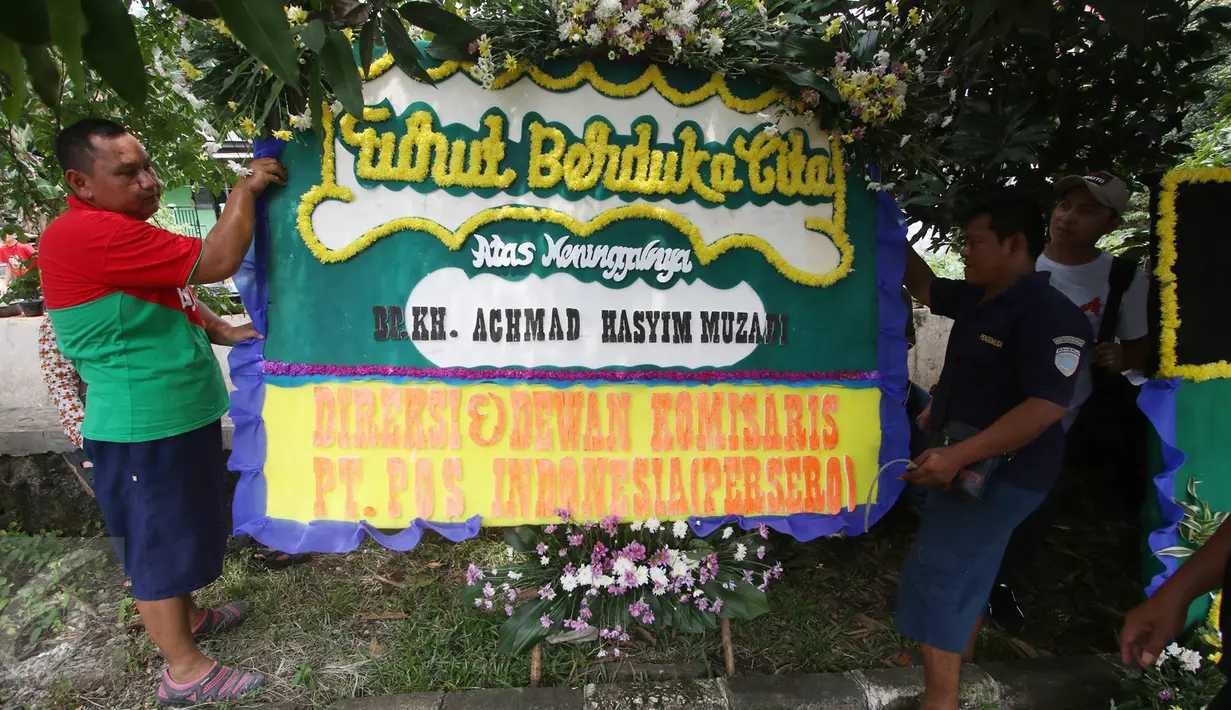 Pekerja menaruh Karangan bunga di rumah duka tokoh PBNU KH Hasyim Muzadi di Ponpes Al-Hikam, Depok, Jawa Barat, Kamis (16/3). Karangan bunga mulai berdatangan pascameninggalnya KH Hasyim Muzadi. (Liputan6.com/Immanuel Antonius)