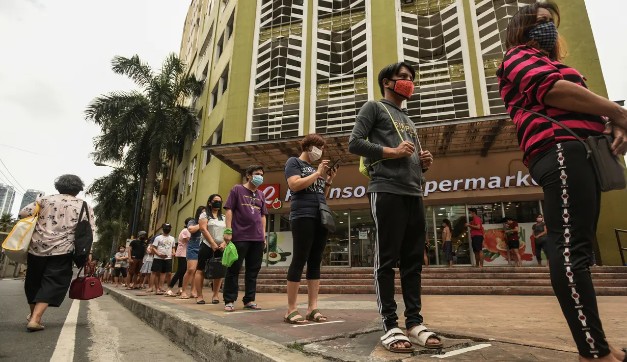 Pembeli berdiri dengan jarak yang aman di garis antrean yang ditempatkan di luar supermarket di Manila, Filipina, Selasa (17/3/2020). Hingga Rabu siang, terdapat 187 positif Virus Corona Covid-19 di Filipina, dengan 12 orang meninggal dan lima orang sembuh.  (Maria TAN / AFP)