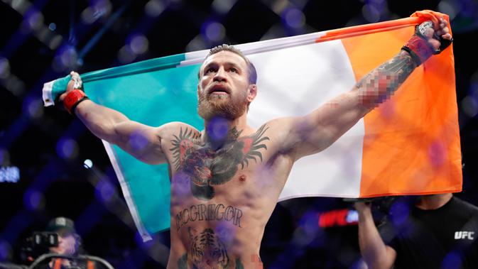 Conor McGregor mengibarkan bendera Irlandia setelah mengalahkan Donald 'Cowboy' Cerrone pada pertarungan kelas welter UFC 246 di T-Mobile Arena, Las Vegas, Amerika Sertikat, Sabtu (18/1/2020). McGregor mengalahkan Cowboy pada detik ke-40. (AP Photo/John Locher)
