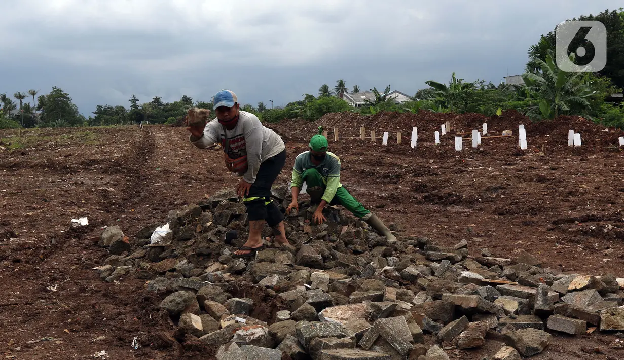 Petugas membuat jalur masuk kendaraan ke area khusus pemakaman jenazah dengan protokol COVID-19 di TPU Srengseng Sawah Dua, Jakarta, Selasa, (2/2/2021). TPU Srengseng Sawah 2, saat ini mulai menerima pemakaman jenazah protokol COVID-19 dengan kapasitas 1.020 petak. (Liputan6.com/Helmi Fithriansyah)