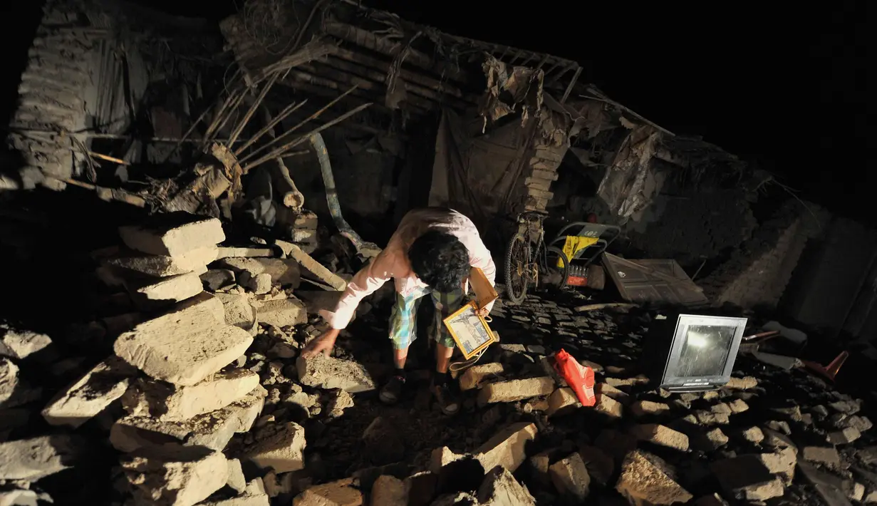 Seorang wanita mengambil barang miliknya di rumahnya yang hancur setelah gempa di Bella Union, Peru, (14/1). Gempa 7,1 skala Richter mengguncang Peru pada Minggu, 14 Januari 2018. (AP Photo / Charlie Reyna)