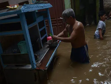 Warga beraktivitas di tengah banjir yang merendam kawasan Kebon Pala, Kampung Melayu, Jakarta Timur, Sabtu (16/7/2022). Banjir itu disebut akibat luapan Kali Ciliwung akibat hujan deras yang mengguyur wilayah Jakarta, Bogor, dan Depok sejak Jumat (15/7/2022) malam hingga Sabtu pagi. (merdeka.com/Imam Buhori)