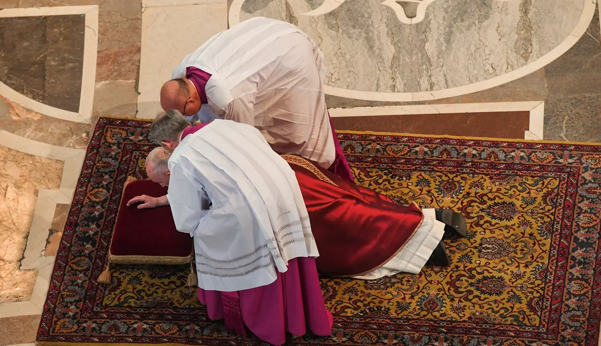 Paus Fransiskus mendapatkan bantuan ketika berdoa sambil berbaring dalam prosesi Jumat Agung memperingati penyiksaan Yesus sebelum disalibkan di Basilika Santo Petrus, Vatikan, Jumat (19/4). (Tiziana Fabi/Pool Photo via AP)