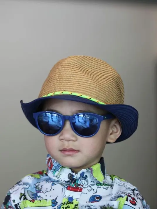 Ganteng banget ga sih anak kecil yang satu inI? Memakai kemeja bermotif kartun, Rafathar makin menggemaskan dengan kacamata hitam dan topinya. Terlebih senyuman di bibir mungilnya juga lucu banget. (Instagram/raffinagita1717)