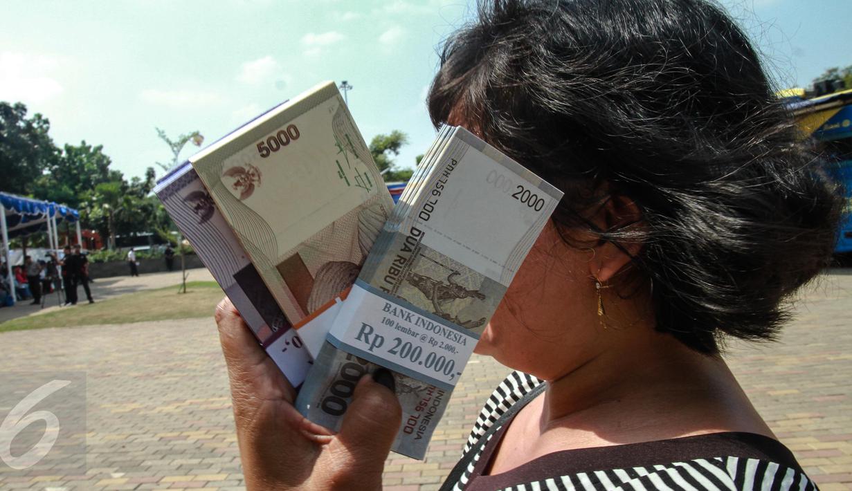 Warga saat menunjukkan uang pecahan Rupiah di gerai penukaran uang receh di Monas, Jakarta, Selasa (30/6). Bank Indonesia bekerjasama dengan 14 bank lainnya membuka loket penukaran uang pecahan kecil sejak 17 Juni-15 Juli 2015 (Liputan6.com/Faizal Fanani)