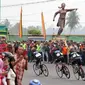 Para pebalap saat melewati Tugu Siti Manggopoh, Simpang Gudang, Kabupaten Agam di Etape 8 Tour de Singkarak 2015 Pasaman Barat-Lawang Park, Kabupaten Agam, Sabtu (10/10/2015). (Bola.com/Arief Bagus)