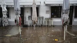 Payung memiliki tanda ketinggian yang dicapai air di luar sebuah restoran yang banjir semalaman di Alges, tepat di luar Lisbon, Selasa (13/12/2022). Badai Atlantik menghantam semenanjung Iberia, meninggalkan jejak kehancuran pada Selasa, terutama di Ibu kota Portugal,  Lisbon, sebelum pindah ke timur ke Spanyol.  (AP Photo/Armando Franca)