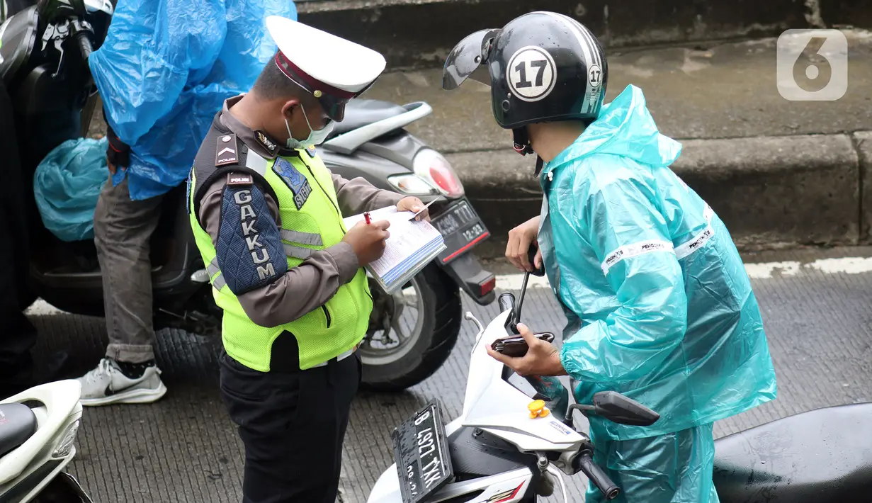 Petugas kepolisian menuliskan surat tilang buat pengendara motor yang melintasi jalur bus Transjakarta di Jalan Sultan Agung, Manggarai, Jakarta, Kamis (6/2/2020). Meski melanggar, sebagian pengguna jalan sengaja masuk dan menggunakan jalur khusus bus tersebut. (Liputan6.com/Helmi Fithriansyah)