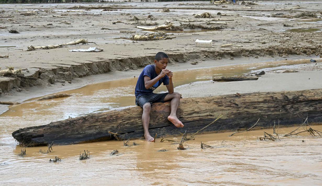 Proses evakuasi dan penyelamatan masih berlangsung di beberapa titik. Akses jalan menuju Desa Tukka sempat tertutup total oleh tumpukan lumpur, bebatuan, kayu gelondongan, hingga runtuhan tebing. Tampak dalam foto, seorang warga duduk di atas batang kayu di tengah banjir bandang di Desa Tukka, Tapanuli Tengah, Sumatera Utara, pada 2 Desember 2025. (YT HARIONO/AFP)