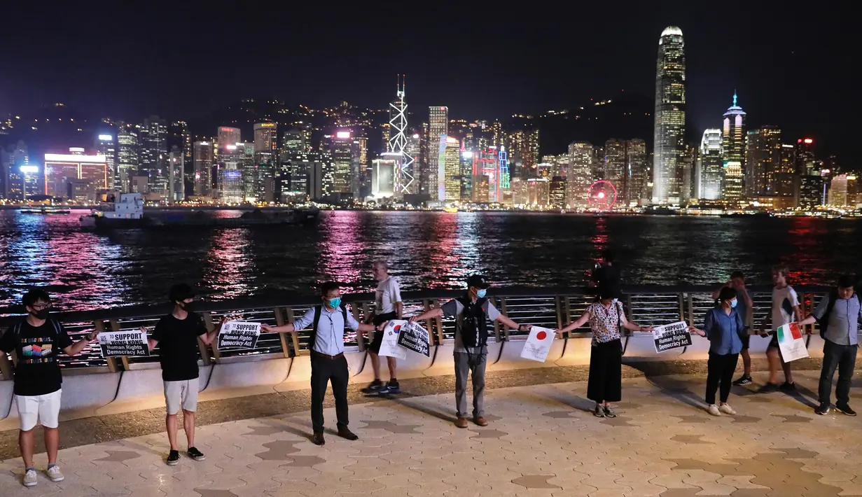 Demonstran prodemokrasi membentuk rantai manusia di tepi pantai Tsim Sha Tsui, Hong Kong, Jumat (23/8/2019). Jalur rantai anusia itu membentang terpisah dari Pulau Hong Kong, Semenanjung Kowloon, dan wilayah New Territories dekat perbatasan China daratan. (AP Photo/Vincent Yu)