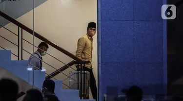 Bupati Bangkalan Abdul Latif Amin Imron membawa koper dan dikawal saat tiba di Gedung Komisi Pemberantasan Korupsi (KPK), Jakarta, Rabu (7/12/2022). KPK menangkap Bupati Bangkalan Abdul Latif Amin Imron sebagai tersangka kasus suap lelang jabatan di Pemerintahan Kabupaten Bangkalan, Jawa Timur. Total kekayaan yang dimiliki Abdul Latif sebanyak Rp 9,9 miliar. (Liputan6.com/Johan Tallo)