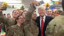 Presiden Donald Trump dan Melania Trump berswafoto dengan pasukan militer Amerika dalam kunjungan kejutan ke Pangkalan Udara al Asad, Irak, Rabu (26/12). Kunjungan ini menuntaskan janjinya untuk mengunjungi salah satu zona perang AS. (SAUL LOEB/AFP)