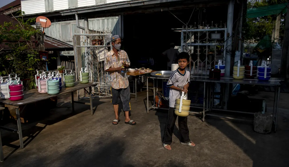 Umat muslim membawa kotak berisi makanan dari Masjid Bang Aw, Bangkok, Thailand, Kamis (30/4/2020). Setiap hari selama Ramadan, sukarelawan membagikan makanan kepada 150 keluarga sekitar Masjid Bang Aw yang tidak bisa beribadah bersama karena pandemi COVID-19. (AP Photo/Gemunu Amarasinghe)