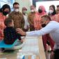 Kepala BKKBN dr hasto Wardoyo (batik cokelat) bersama CEO PTPN V Riau Jatmiko Santosa menyaksikan penimbangan berat badan bayi dalam kegiatan menekan angka stunting di Riau. (Liputan6.com/M Syukur)