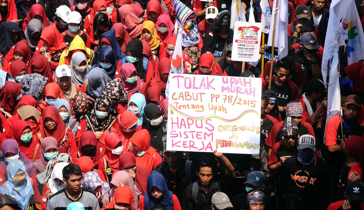 Massa buruh mengacungkan pamplet di ruas Jalan Medan Merdeka Barat saat perayaan hari Buruh Internasional di Kawasan Patung Patung Arjuna Wiwaha, Jakarta, Senin (5/1). Ribuan massa buruh ikut dalam perayaan MayDay 2017. (Liputan6.com/Helmi Fithriansyah) 