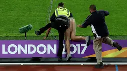 Petugas menangkap seorang pria tanpa busana dalam Kejuaraan Atletik Dunia London 2017 di Stadion London, London, (5/8). Kehidran pria ini sebelum penampilan Usain Bolt di nomor 100 m. (AFP Photo/Daniel Leal-Olivas)