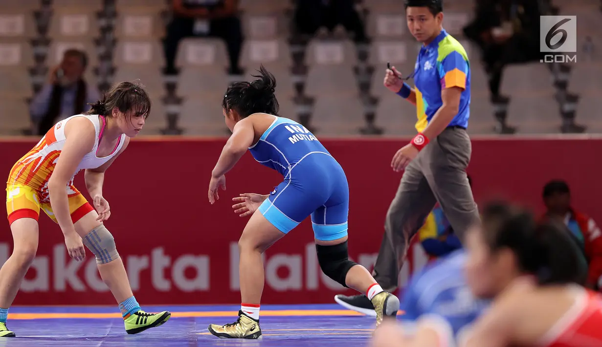 Pegulat Indonesia, Ayuningtias Mutiara (kanan) bertarung dengan pegulat Uzbekistan, Esenbaeva Nabira pada babak perdelapan final 57 kg putri dalam Asian Games 2018 di JCC Senayan, Senin (20/8). Ayuningtias kalah dengan skor 0-7 (Liputan6.com/Fery Pradolo)
