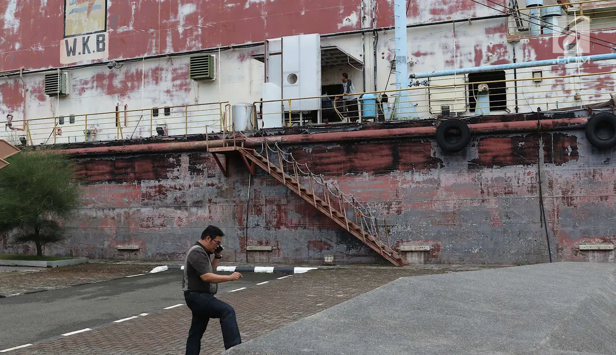 Pengunjung menelepon di sekitar Monumen Kapal Pembangkit Listrik Tenaga Diesel (PLTD) Apung 1 di Aceh, Selasa (31/7). Dari atas kapal ini pengunjung dapat melihat rangkaian pegunungan Bukit Barisan. (Liputan6.com/Immanuel Antonius)