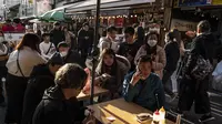 Orang-orang menunggu untuk makan makanan laut di area "pasar ikan luar" Tsukiji di Tokyo pada 28 Desember 2022. Menjelang liburan Tahun Bar, turis asing dan penduduk lokal berkunjung ke pasar itu untuk menikmati hidangan bermacam makanan laut. (AFP/Richard A. Brooks)