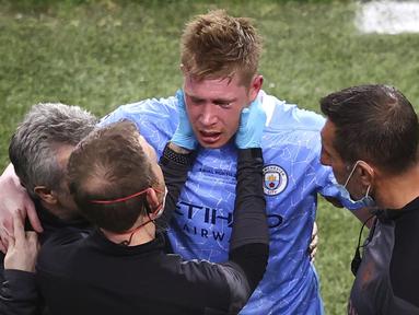 Kevin De Bruyne (tengah) dipapah keluar lapangan setelah menjalani perawatan karena tabrakan dengan Antonio Rudiger selama pertandingan final Liga Champions antara Manchester City dan Chelsea di Stadion Dragao di Porto, Portugal, Sabtu (29/05/2021) waktu lokal. (Foto: AP/Pool/Michael Steele)