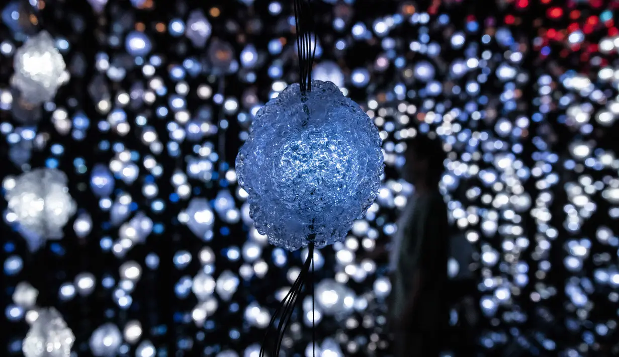 Orang-orang mengunjungi "Pixel Forest" oleh seniman Swiss Pipilotti Rist, sebuah instalasi seni dari 3000 lampu LED pahatan tangan yang digantung di langit-langit di Tai Kwun di Hong Kong (18/8/2022). (AFP/Isaac Lawrence)