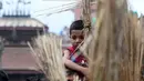 Seorang anak Nepal membawa jerami yang digunakan untuk membuat patung Ghantakarna selama perayaan festival Hindu "Gathemangal" di kota kuno Bhaktapur, Nepal (30/7/2019). (AFP Photo/Prakash Mathema)